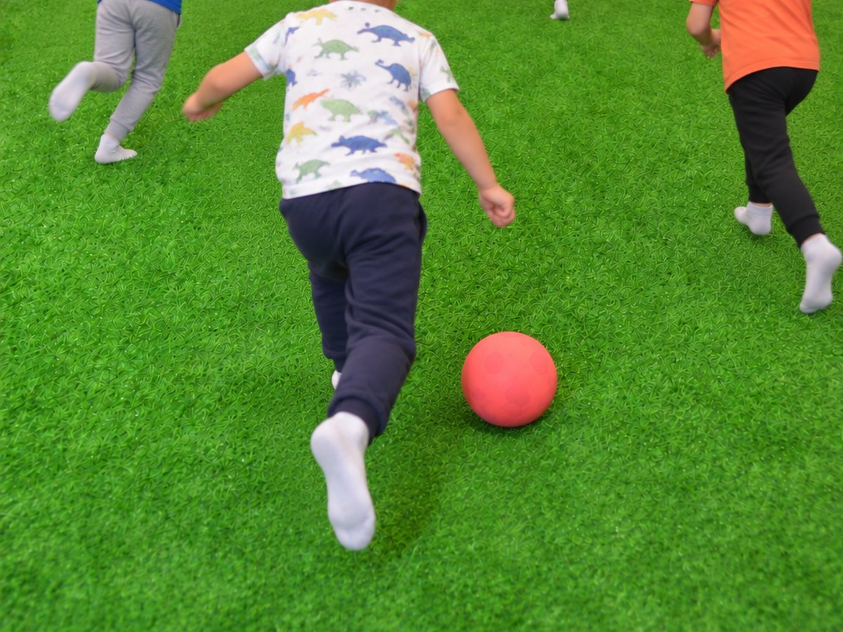 Copii alergând după minge pe terenul de fotbal acoperit de la Happy PlayTime Arad